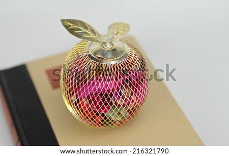 A wire apple filled with potpourri on a book as a teacher\'s gift