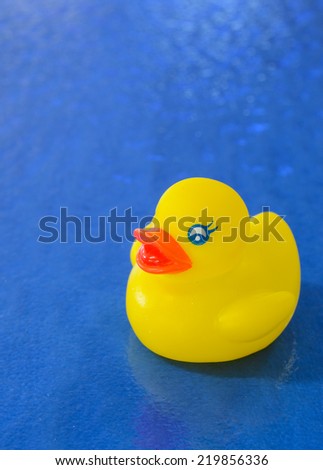Bright yellow rubber duck on blue textured glass surface