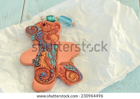 Pottery gingerbread bear tree ornament in rich teals and golds on paper wrapping