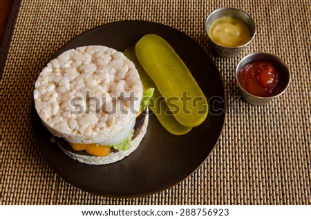 An alternative hamburger made with rice cakes for gluten free diets, with cheese, ketchup, mustard and fixings