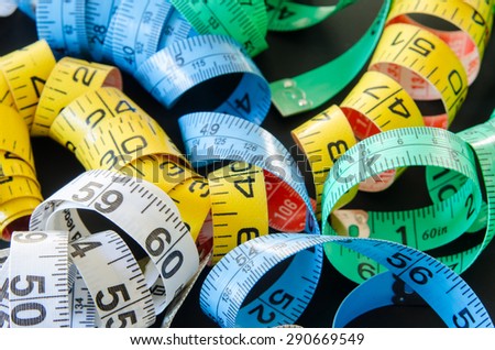 Green, Yellow, blue and white measuring tapes on a black background