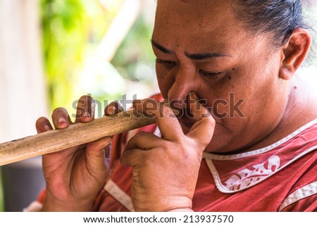 MOOREA, FRENCH POLYNESIA - CIRCA 2014: Polynesian woman plays traditional nose flute circa 2014 in Moorea. Polynesian nose flute is popular traditional musical instrument of French Polynesia.