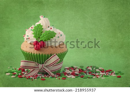 Christmas cup cakes with holly berry on a green background