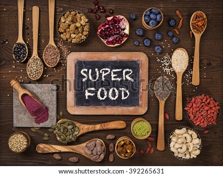 Super foods in spoons and bowls on a wooden background