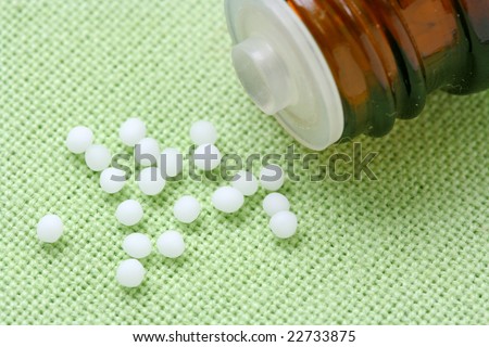 Homeopathic medicine and bottle on green