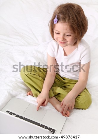Little girl with laptop on the bed