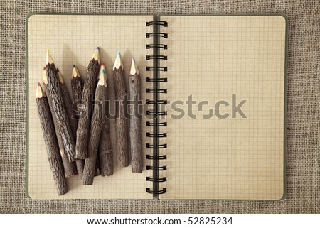 Wooden color pencils and exercise book on brown background