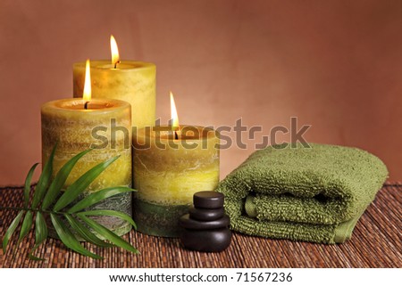 Spa products with green candles, stones and towel