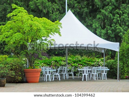 Tables under the tent create outdoor eating area in the lush greenery