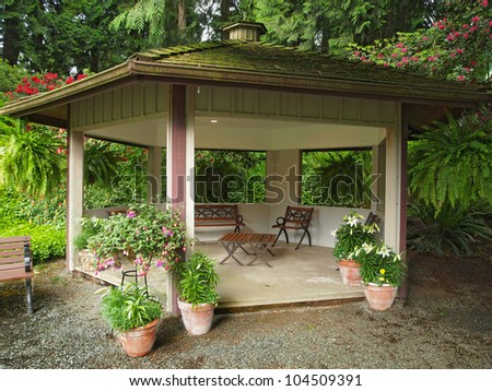Wooden gazebo with roof covered with moss in the garden