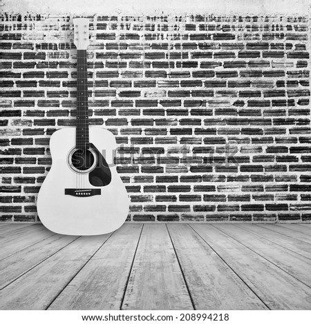 acoustic guitar in empty room with brick wall background