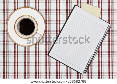 notebook and cup of coffee on picnic tablecloth
