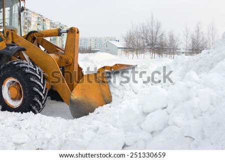 The bulldozer clears away snow drifts