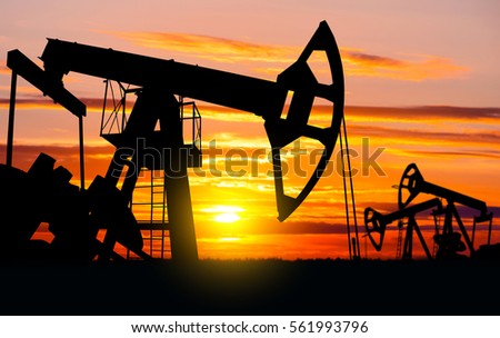 Industrial landscape. Oil Field. Oil pumps against the setting sun.