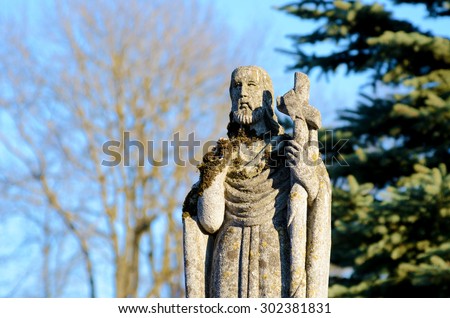 Old stone statue at the tomb of St. Peter in the old cemetery on the background of the sky in Ukraine