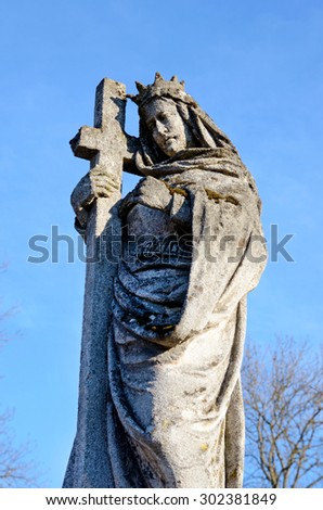 A stone statue of Jesus Christ on the grave in the old cemetery on the background of the sky