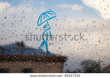 Picture of man with an umbrella on a window in the drops of rain