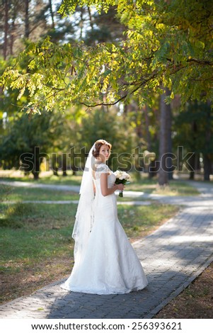 beautiful wedding bouquet of flowers in hands of young bride. weddings. young woman touches flowers with hand. wedding celebration. reception. nature green background. woman alone outdoors in park