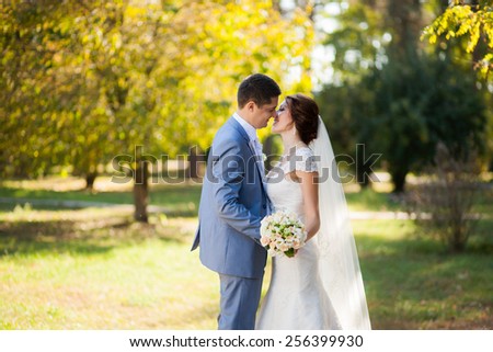 happy bride, groom standing in green park, kissing, smiling, laughing. lovers in wedding day. happy young couple in love. new family lifestyles. beautiful healthy people. nature background. woman man