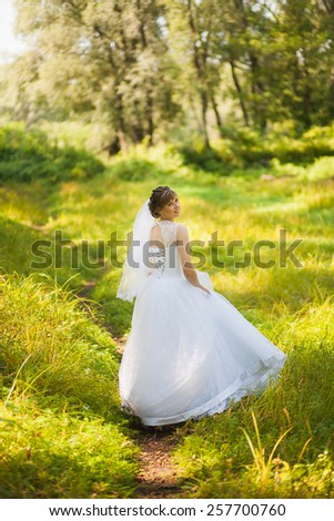 portrait of beautiful young bride in green summer park. woman in white wedding dress. wedding celebration. reception. nature background. vertical photo