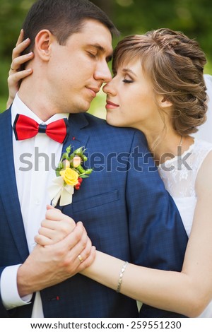 happy bride, groom holding hands in green park, kissing, smiling, laughing. lovers in wedding day. happy young couple in love. new family lifestyles. beautiful people. nature background. woman man