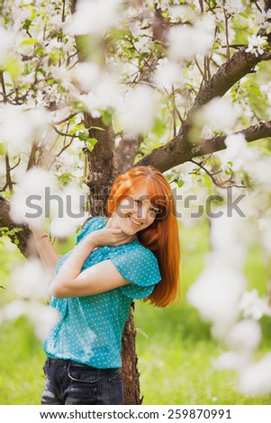 Free Happy Woman with Gorgeaos Red Hair Enjoying Nature. Beauty Young Girl Outdoor in Spring Garden. Freedom concept. Healthy Smiling Girl over Green Flowers Nature Background. Apple-trees in Blossom