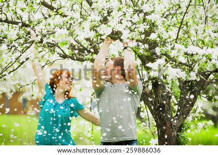 beautiful couple in love having fun outdoors in spring garden full of blooming apple-trees