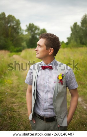 Portrait of handsome young man smartly dressed. Boutonniere. Red Bowtie. Stylish person