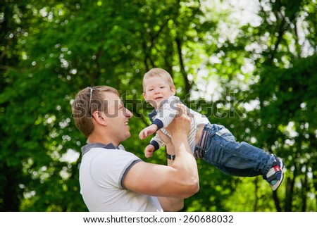 Happy family having fun outdoors in spring garden. Father playing with child. Family concept. Picnic. Man holding little boy in hands. Laughing, smiling people.