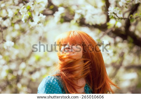 Free Happy Woman with Gorgeous Red Hair Enjoying Nature. Beauty Young Girl Outdoor in Spring Garden. Freedom concept. Healthy Smiling Girl over Green Flowers Nature Background. Apple-trees in Blossom
