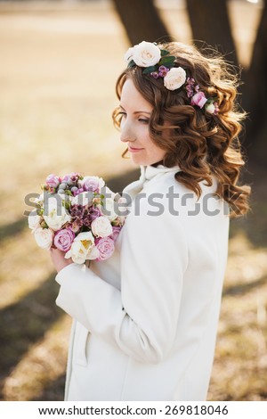 Beautiful young woman with delicate flowers in hair and bouquet of flowers in hands