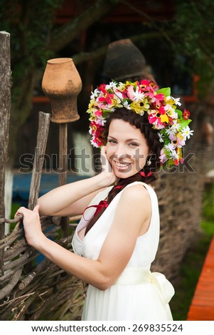 Portrait of beautiful smiling young woman with flower wreath in hair