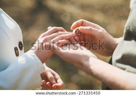 Wedding rings. Hands of bride and groom. Wedding ceremony. Wedding couple. Wedding celebration. Newlyweds. Man and woman with golden ring. Close up groom puts  wedding ring on bride