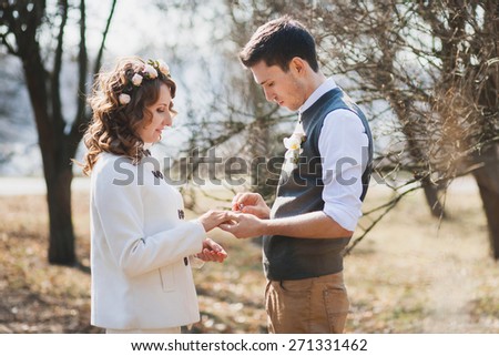 Bride and groom exchanging wedding rings. Wedding couple. People in love. Young man and beautiful woman in spring park. Marriage proposal. Outdoors wedding ceremony. Happy people