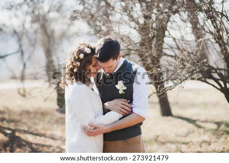 beautiful wedding couple hugging and kissing outdoors in spring sunny park. wedding couple in love in wedding day. two happy people. woman and love outside over beautiful landscape