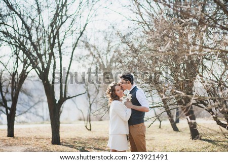 beautiful wedding couple hugging and kissing outdoors in spring sunny park. wedding couple in love in wedding day. two happy people. woman and love outside over beautiful landscape