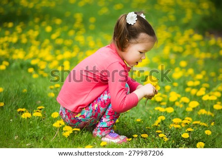cute pretty little girl  with yellow dandelions. spring day. Child playing outside in warm spring day in meadow full of spring flowers