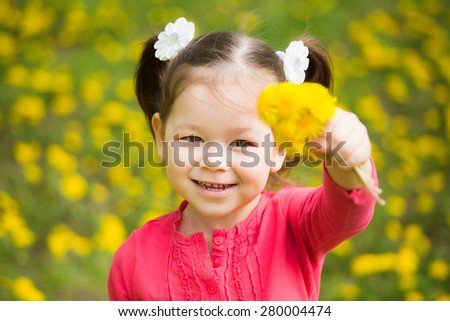 cute pretty little girl  with yellow dandelions. spring day. beautiful cheerful child playing with flowers in spring day in meadow. baby holding bouquet of spring flowers in hand and looking at camera