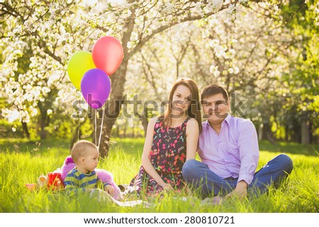 family picnic. father, mother, child sitting together on blanket in spring garden in warm sunny day. family portrait. sunset people. happy family concept. people on weekend having fun outside .