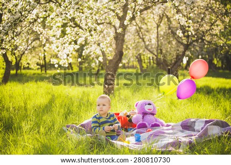 family picnic.child sitting among toys on blanket in spring garden in warm sunny day. family portrait. sunset people. happy family concept. people on weekend having fun outside .