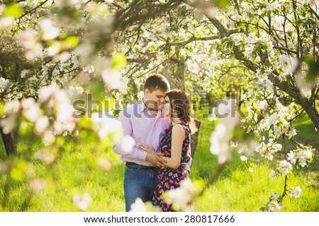 couple in love standing in spring blooming garden. man and woman hugging outsie. people face to face portrait. family and love concept.