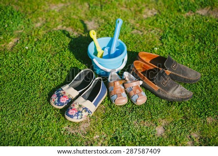 Family shoes in grass in park. Parents and child shoes. Three pairs of shoes of father, mother and son or daughter. Family, growth, love and togetherness concept.