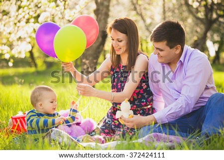 Family on picnic. Dad and mom playing games with little son outside in spring blooming garden. Happy family activity. Portrait of woman, man and little boy at sunny trees with spring flowers.