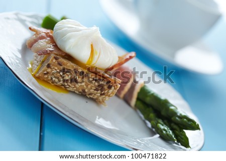 Poached egg and bacon on whole wheat toast with green asparagus
