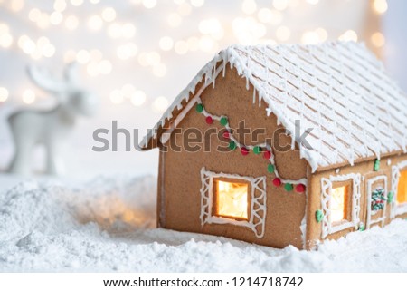 Gingerbread house in snow with twinkling silver light background