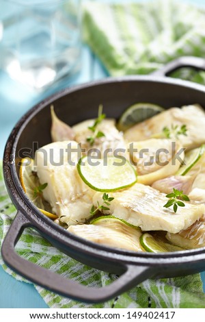 Baked fish fillet with lemon, lime, garlic and themy