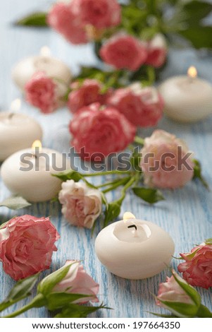 Pink roses and candles on a blue wooden table