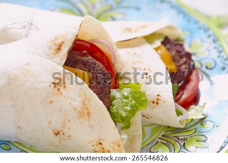 Fresh tortilla wrap with grilled beef burger and vegetables