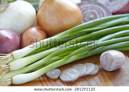 Red, white and yellow onions on rustic wooden background