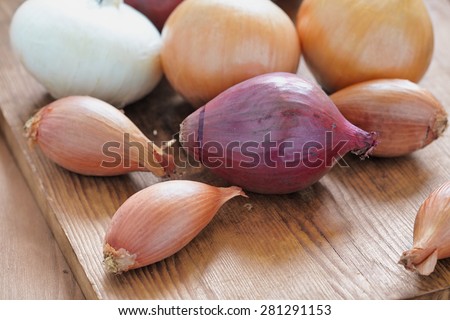 Red, white and yellow onions on rustic wooden background